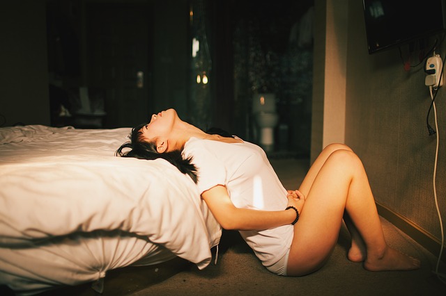 Žena v bielom tričku je opretá v sexy póze o posteľ.jpg